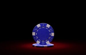 A blue poker chip against a dark red and black background representing the disadvantages of blue chip stocks.